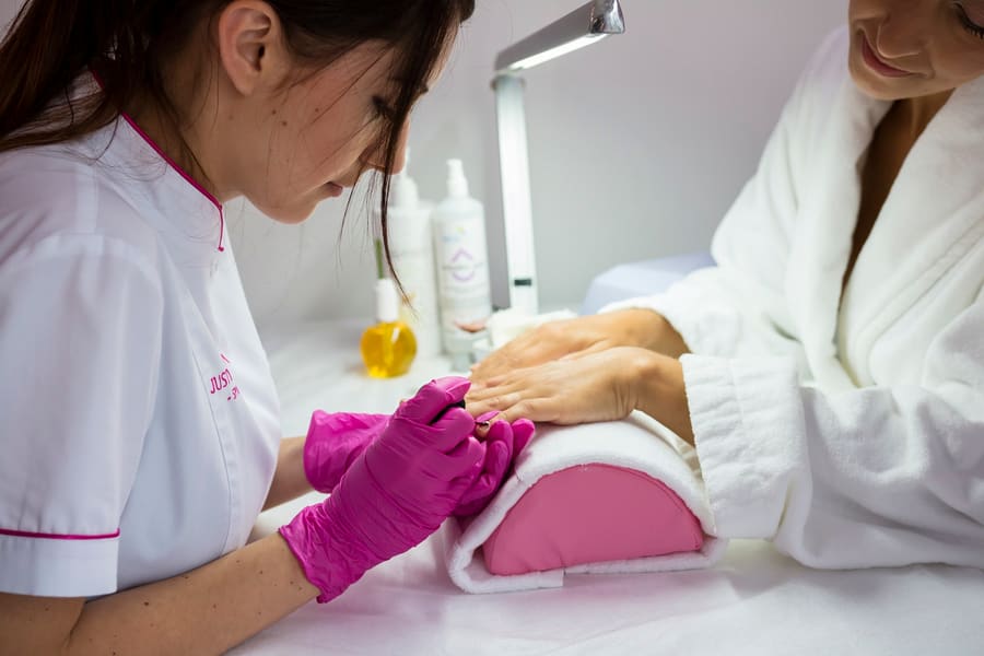 Manicure fazendo unhas de uma cliente em spa